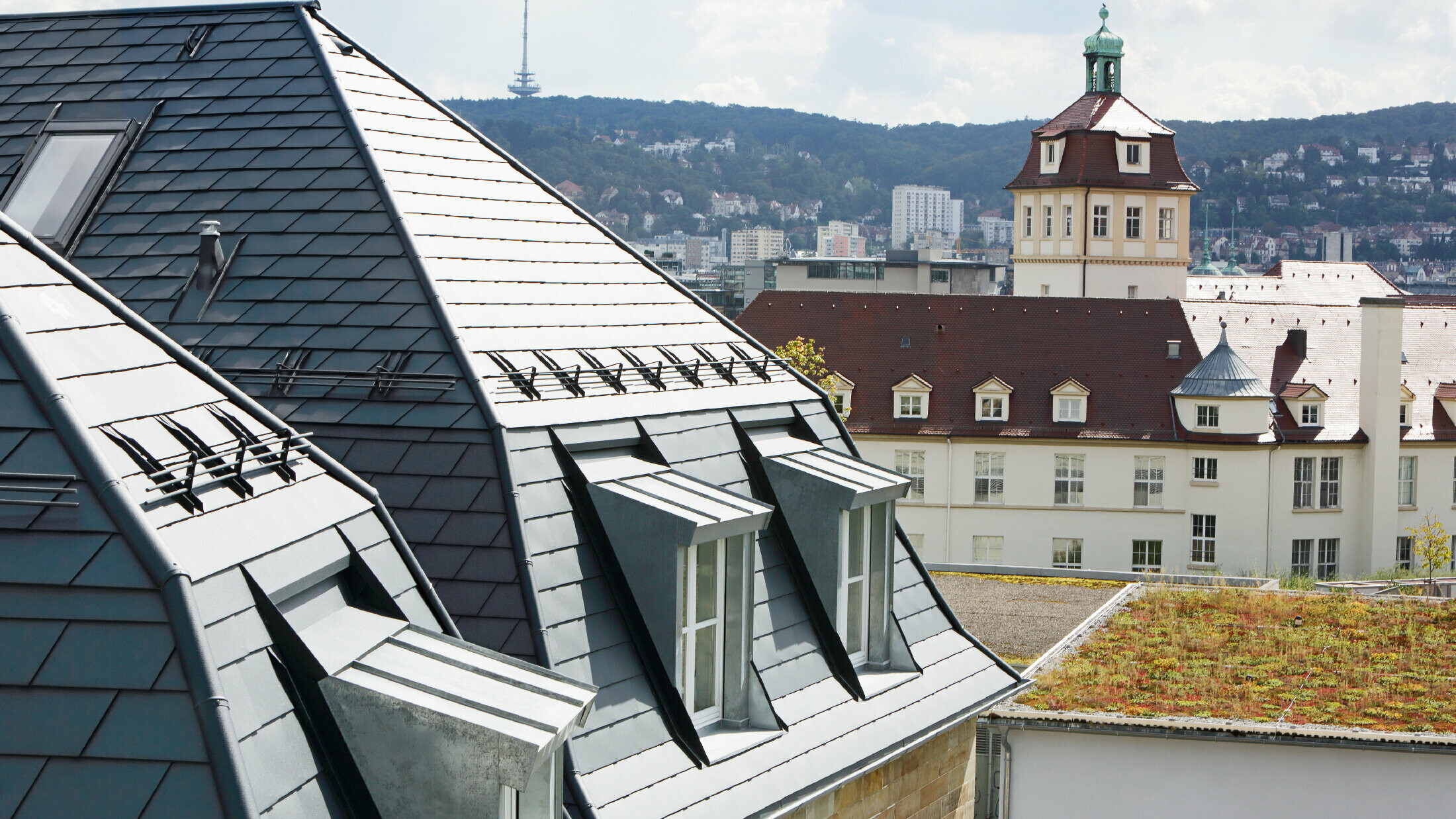 Maison de ville ancienne à Stuttgart, avec toit mansardé recouvert de bardeaux en aluminium PREFA en P.10 anthracite et nombreuses fenêtres-lucarnes