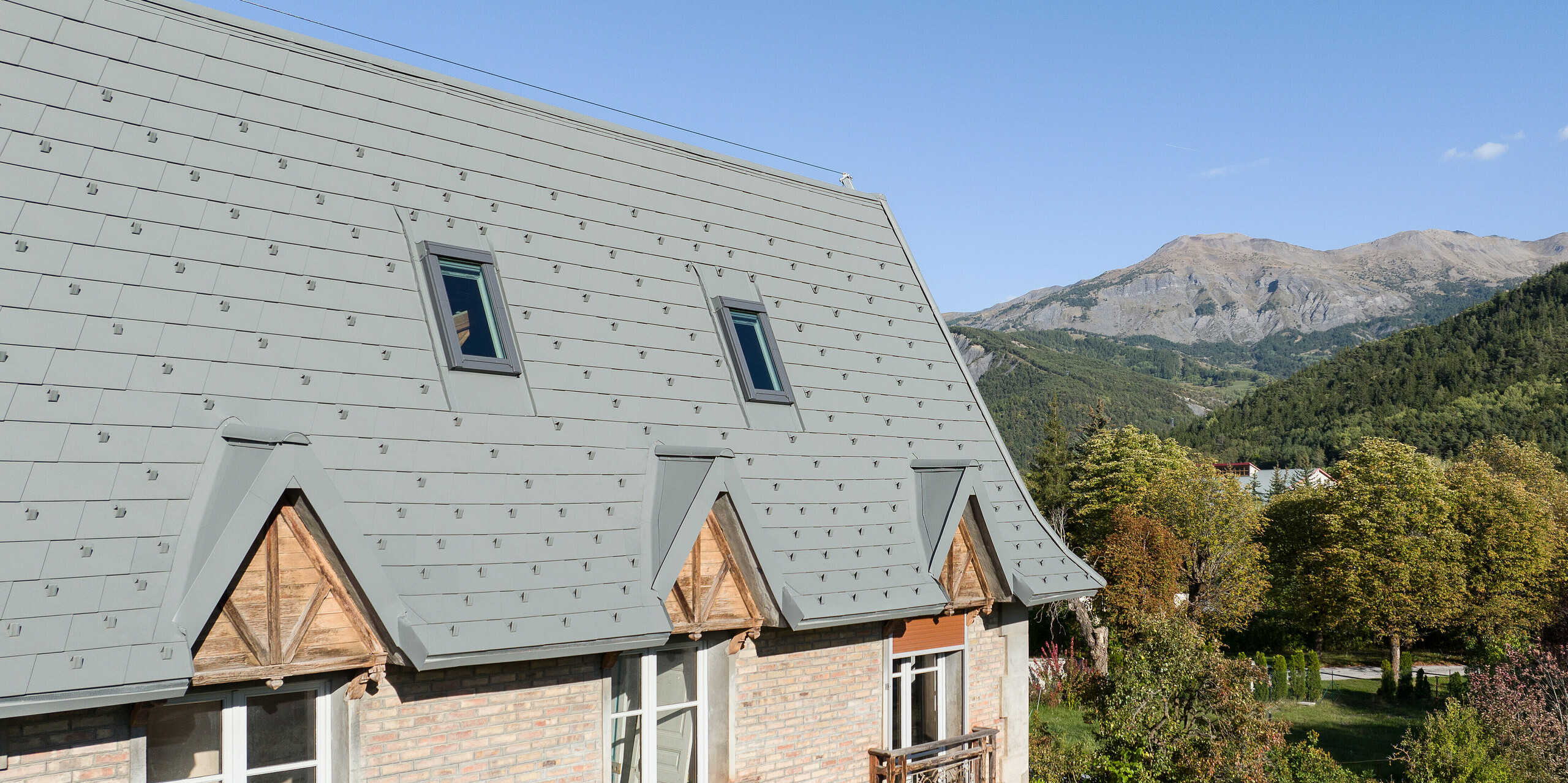 Die großflächige Dachlandschaft eines Anwesens in Barcelonnette, Frankreich wurde mit der PREFA Dachschindel in P.10 Hellgrau saniert. 