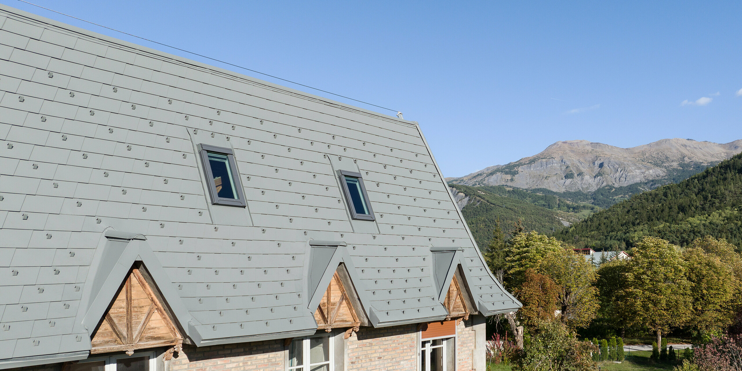 La vaste toiture d'une propriété à Barcelonnette, en France, a été rénovée avec le bardeau de toiture PREFA en P.10 gris souris.