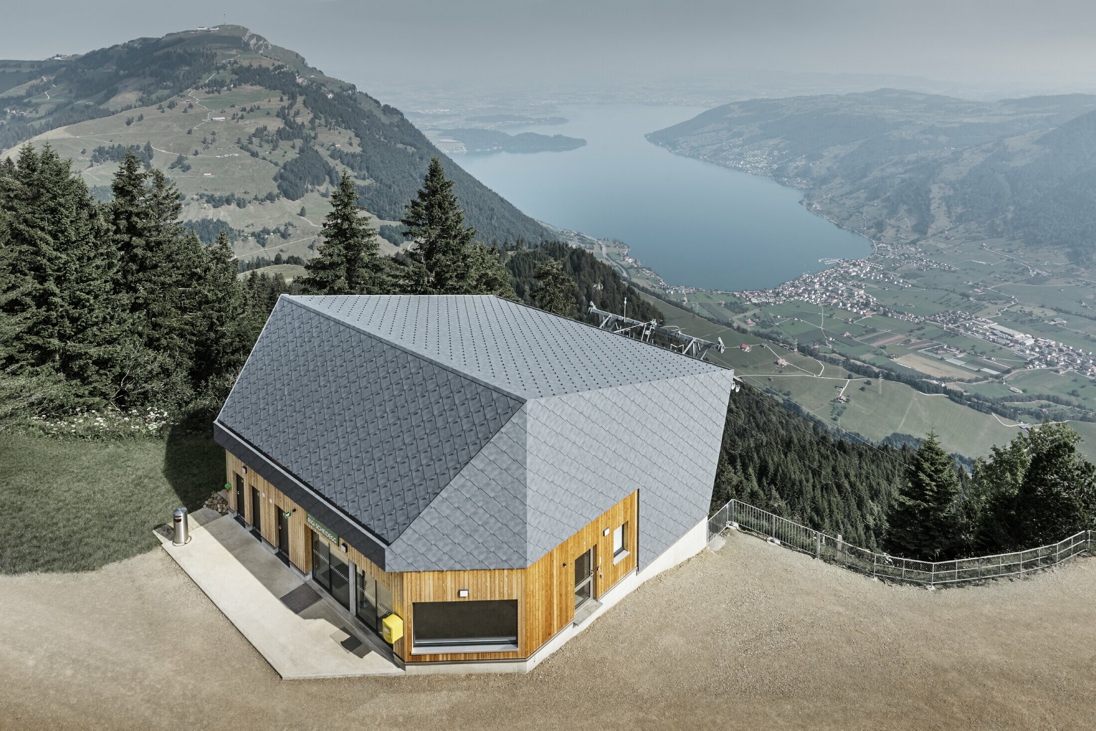 Vue aérienne de la gare d’arrivée du téléphérique du Rigi Scheidegg recouverte de losanges de façade 44 × 44 PREFA couleur P.10 gris pierre et bois.