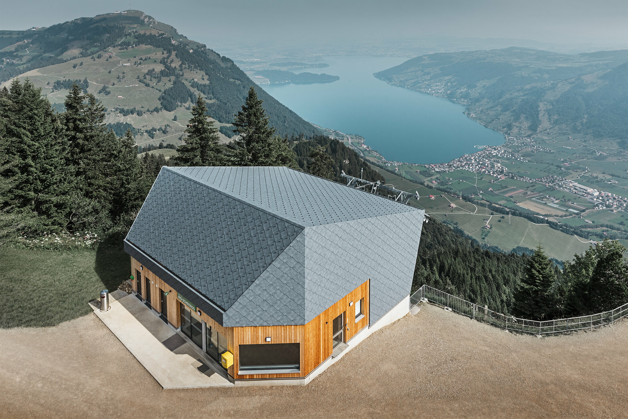 Vue aérienne de la gare d’arrivée du téléphérique du Rigi Scheidegg recouverte de losanges de façade 44 × 44 PREFA couleur P.10 gris pierre et bois.