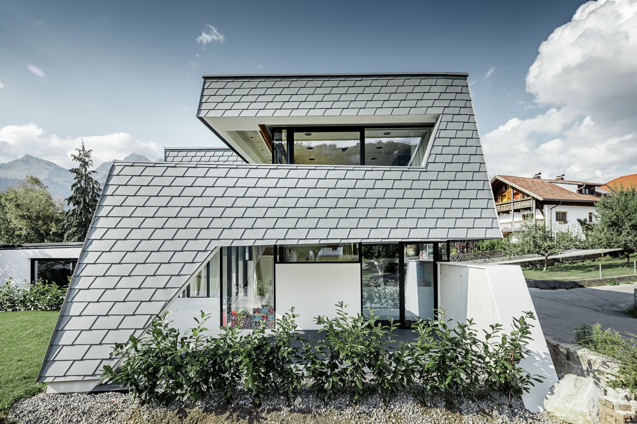 Maison individuelle moderne au toit plat avec de grandes baies vitrées — Façade réalisée avec des bardeaux PREFA en aluminium de couleur gris souris