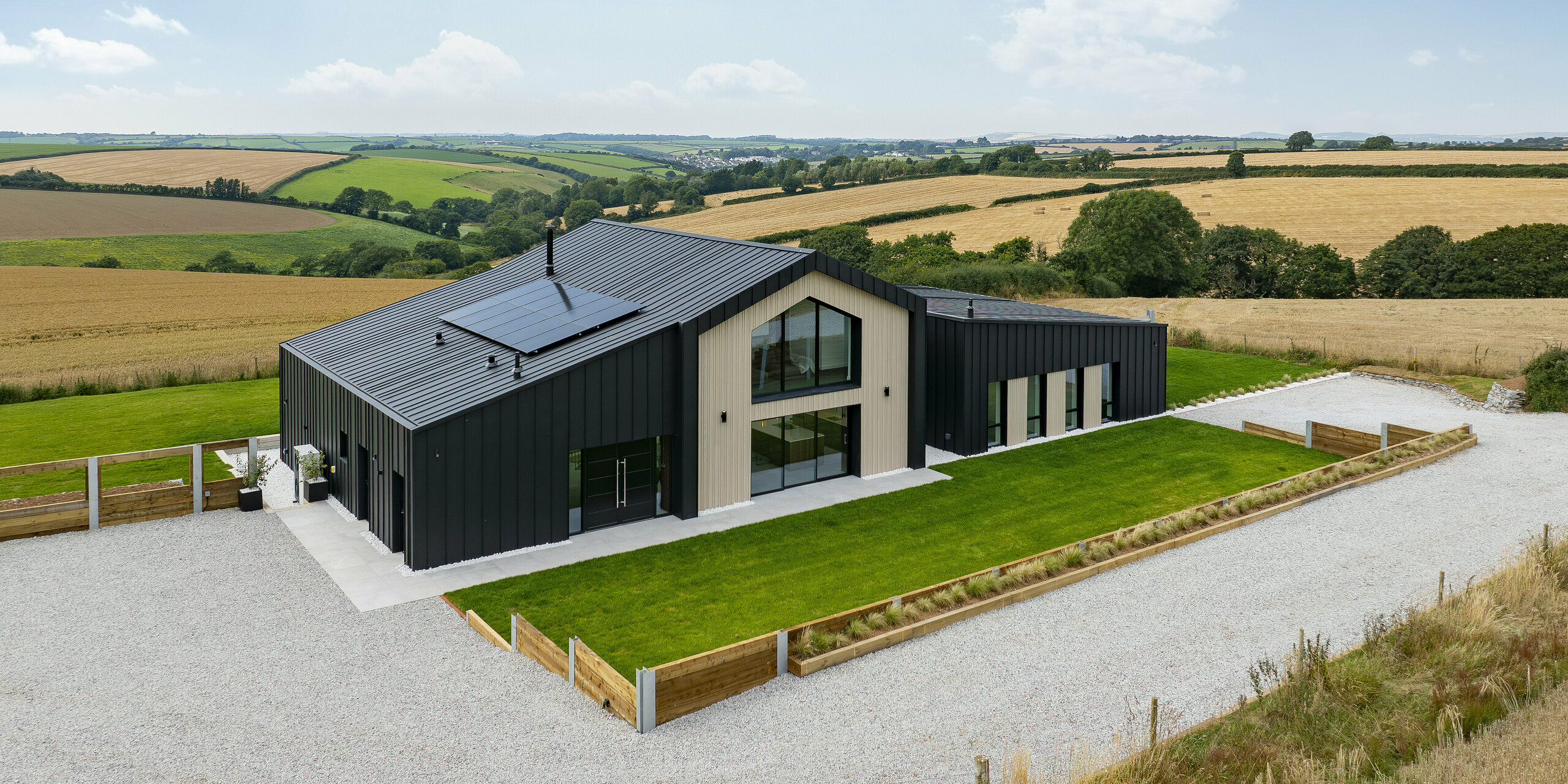 La façade de la maison familiale moderne « The Hide » montre la combinaison harmonieuse d’un design contemporain et d’une architecture de haute qualité. La toiture à joint debout PREFALZ de couleur 0P.10 anthracite recouvre le toit et la façade et forme avec les généreuses surfaces vitrées et les accents en bois une unité visuellement attrayante.