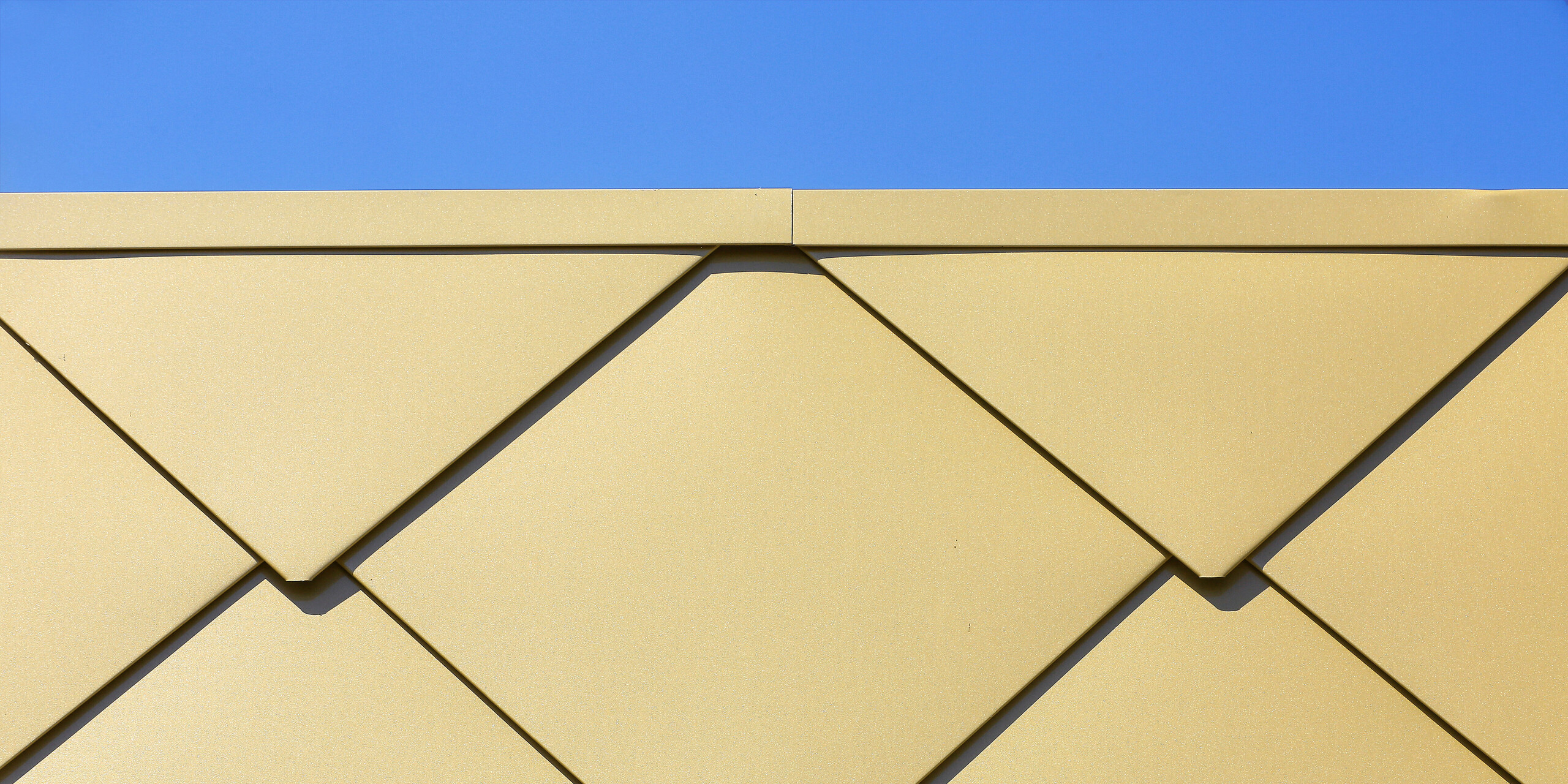 Photo détaillée des losanges de façade étincelants PREFA 44 × 44 en Sparkling Gold au Centre Culturel de Fessenheim en France.