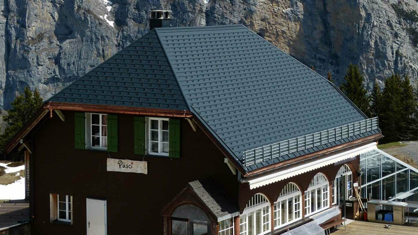 Dachsanierung einer Berghütte mit Krüppelwalmdach mit der PREFA Dachschindel und Schneestoppern