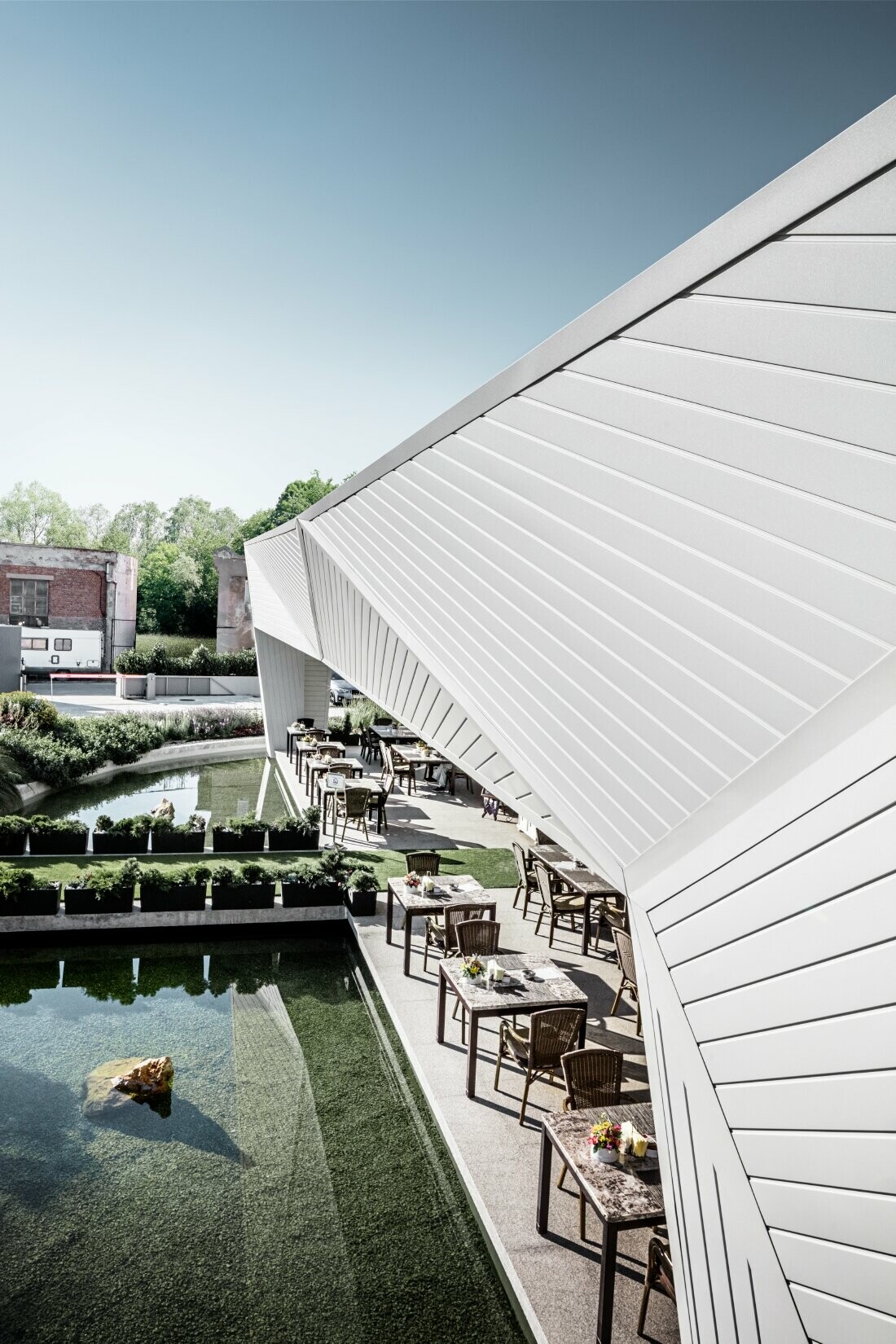 Jardin privé du restaurant Mimama à Budapest avec sa façade 3D recouverte de Sidings PREFA en blanc PREFA.