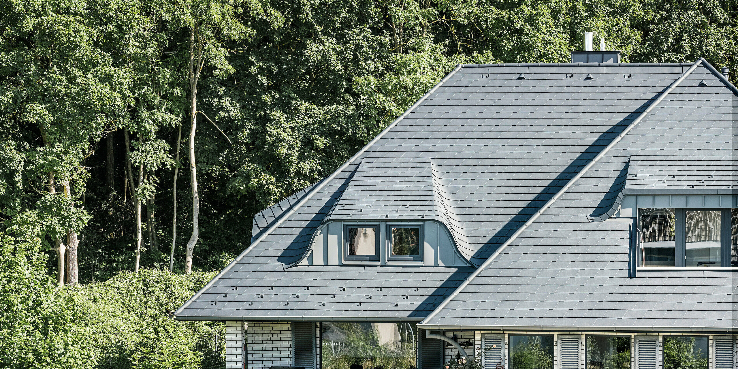 Toiture avec lucarnes cintrées d'une maison individuelle à Einbeck recouverte de bardeaux PREFA en anthracite P.10