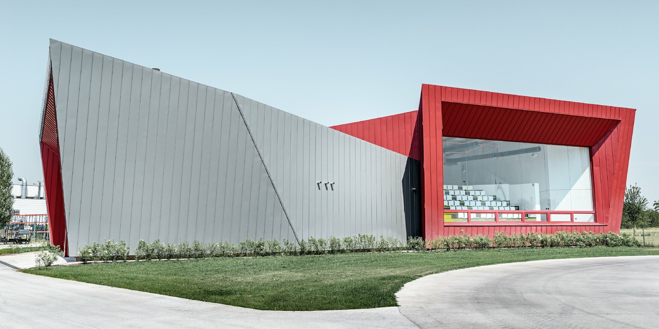 modernes Trainingscenter von Dieci in Montecchio Emilia ,Italien, mit Tribüne mit Aluminiumfassade mit Prefalz in hellgrau und Falzonal in karminrot 