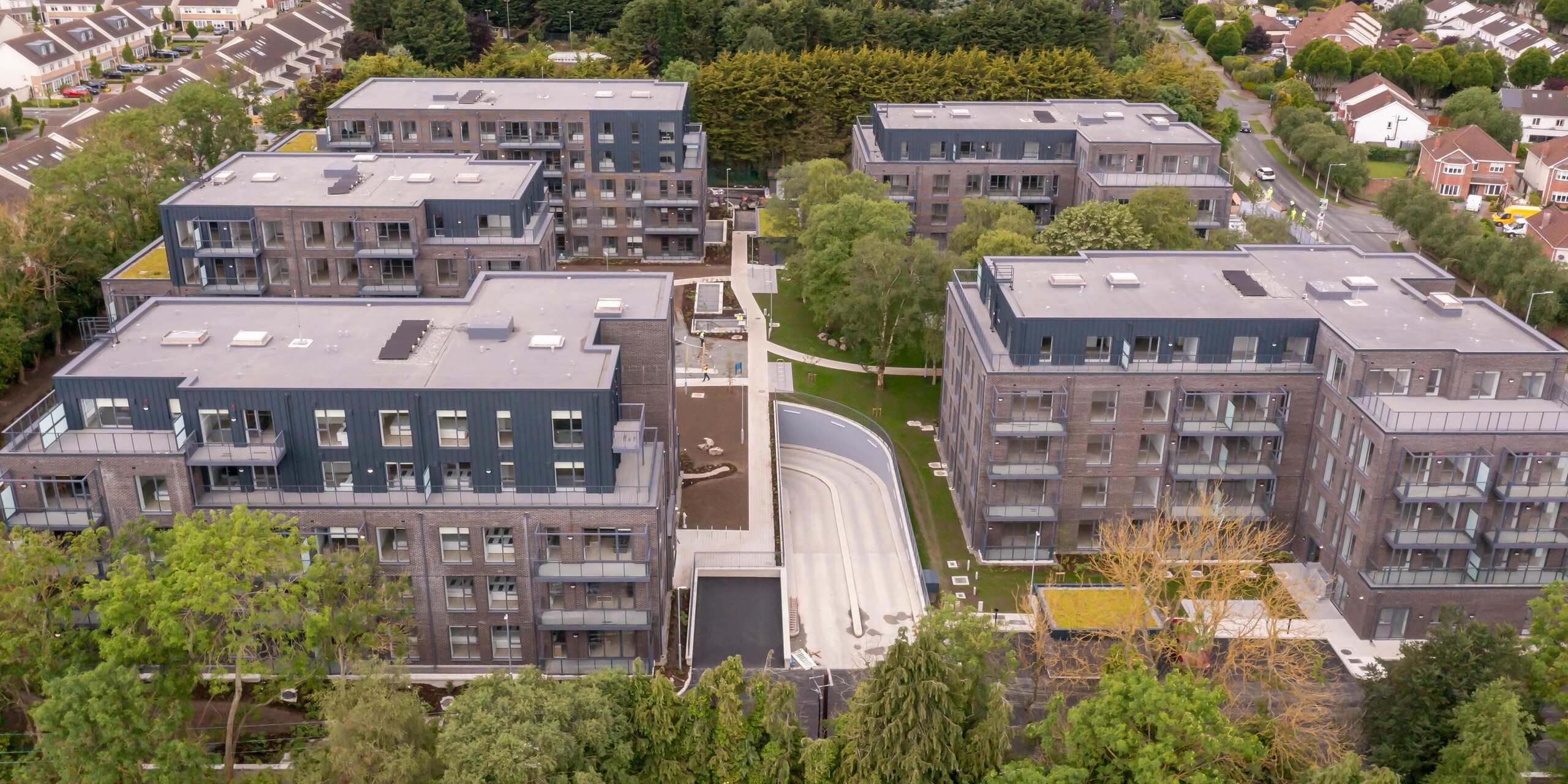 Vue panoramique du complexe résidentiel Balroy Hall à Carpenterstown, Dublin. L'architecture moderne combine une façade en aluminium en PREFALZ en P.10 anthracite avec une brique traditionnelle. La façade métallique durable a été installée sur une superficie de 800 m² et sublime les bâtiments. Le design urbain s'harmonise avec l'environnement.