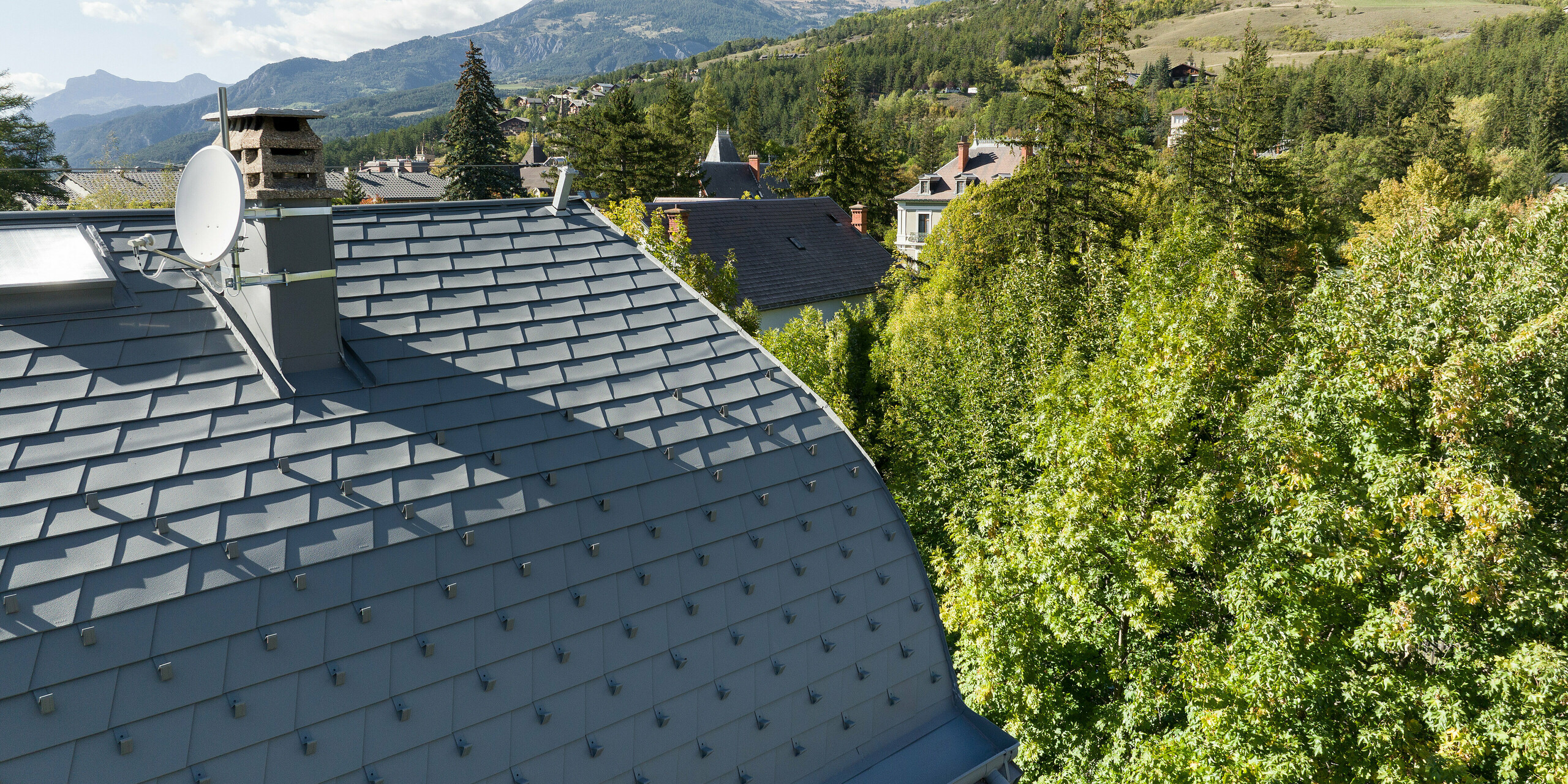 La vaste toiture d'une propriété à Barcelonnette, en France, a été rénovée avec le bardeau de toiture PREFA en P.10 gris souris.