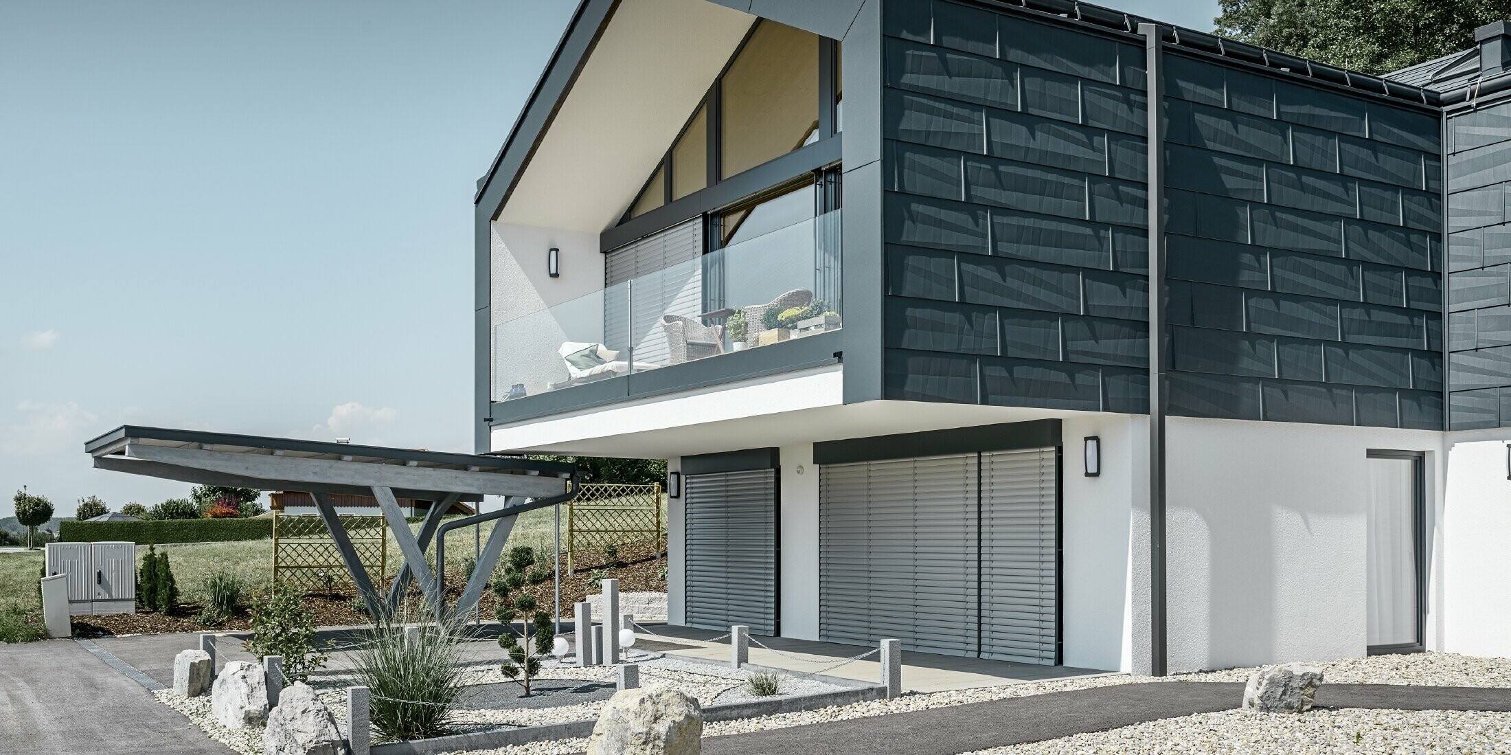 Modernes Mehrfamilienhaus mit einer großen Fensterfront, Dach und Fassade wurden mit dem Dach- und Fassadenpaneel FX.12 in anthrazit von PREFA bekleidet