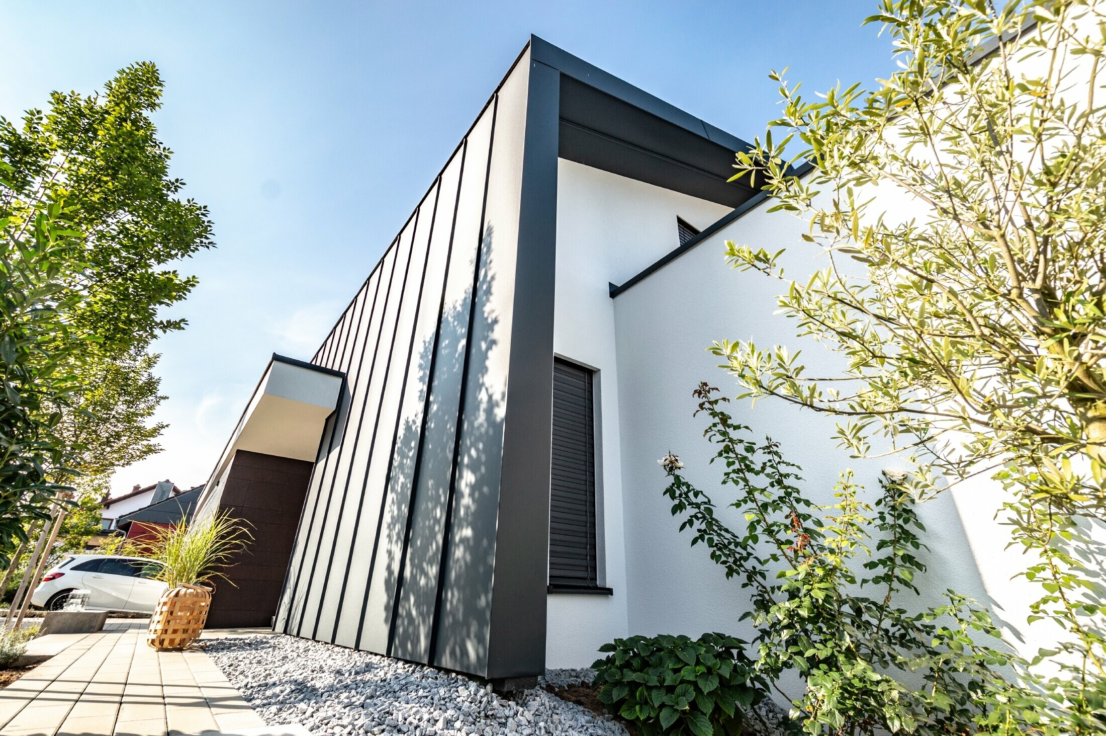 La façade Prefalz de PREFA couleur anthracite se prolonge sur le toit à deux pans de la maison individuelle.