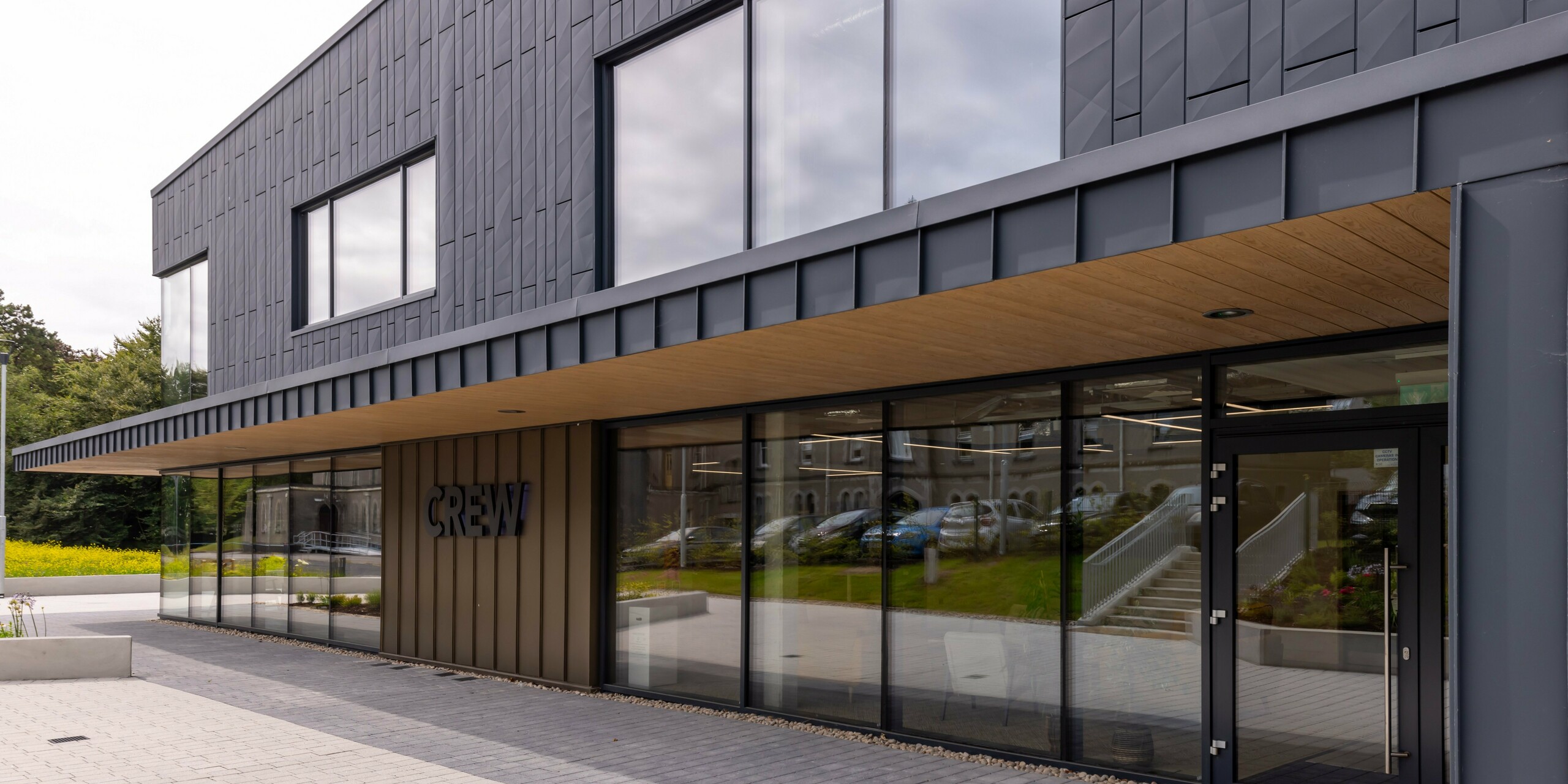 Façade moderne du bâtiment CREW à Galway, Irlande, conçue avec des panneaux de façade PREFA Siding.X et PREFALZ de couleur P.10 anthracite. Le revêtement robuste en aluminium confère à la structure une esthétique élégante et contemporaine. Des lignes claires, des surfaces vitrées généreuses et des matériaux de haute qualité soulignent l'architecture innovante du centre de bureaux.