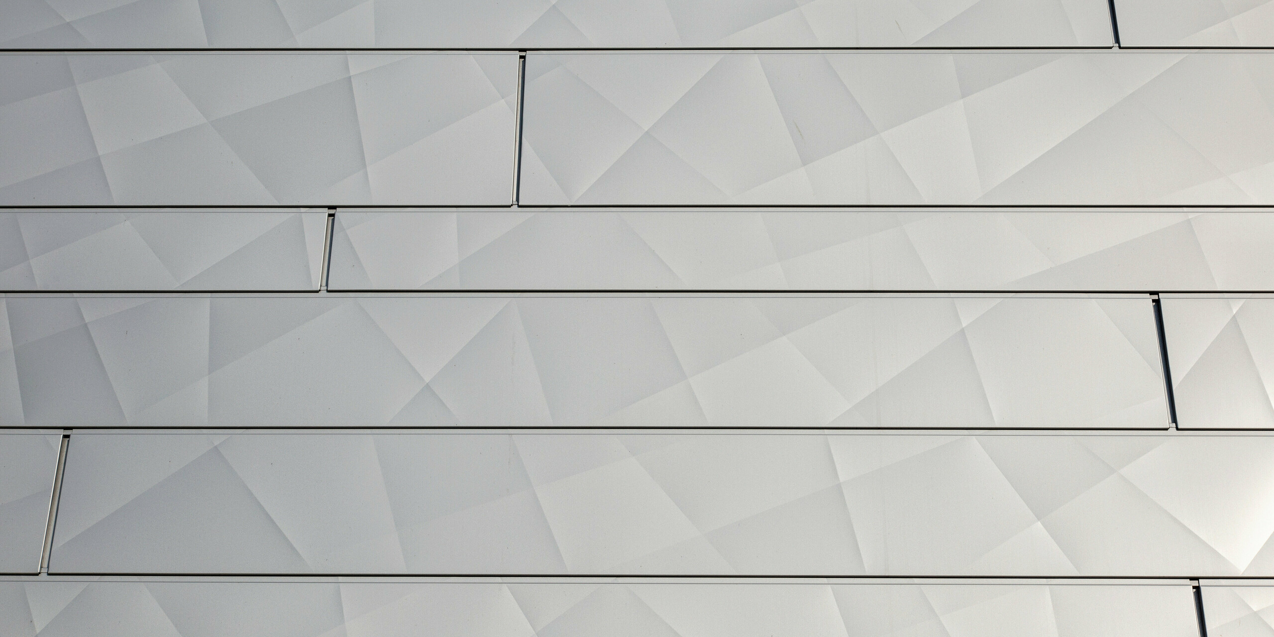 Vue détaillée des panneaux de façade scintillants PREFA Siding.X en argent métallisé dans l'atelier à Auray, France