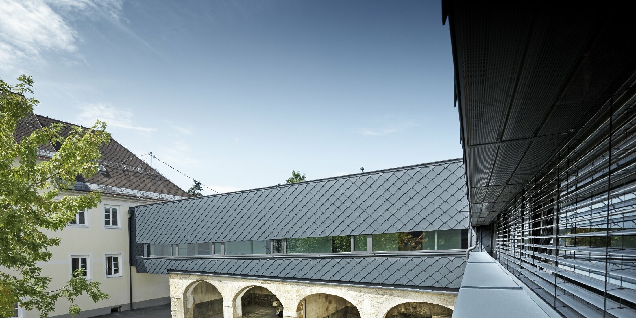 L’étage de ce bâtiment classé est revêtu avec le losange de façade PREFA 29 x 29 en anthracite : les anciennes structures du rez-de-chaussée s’harmonisent ainsi parfaitement avec les nouveaux losanges.