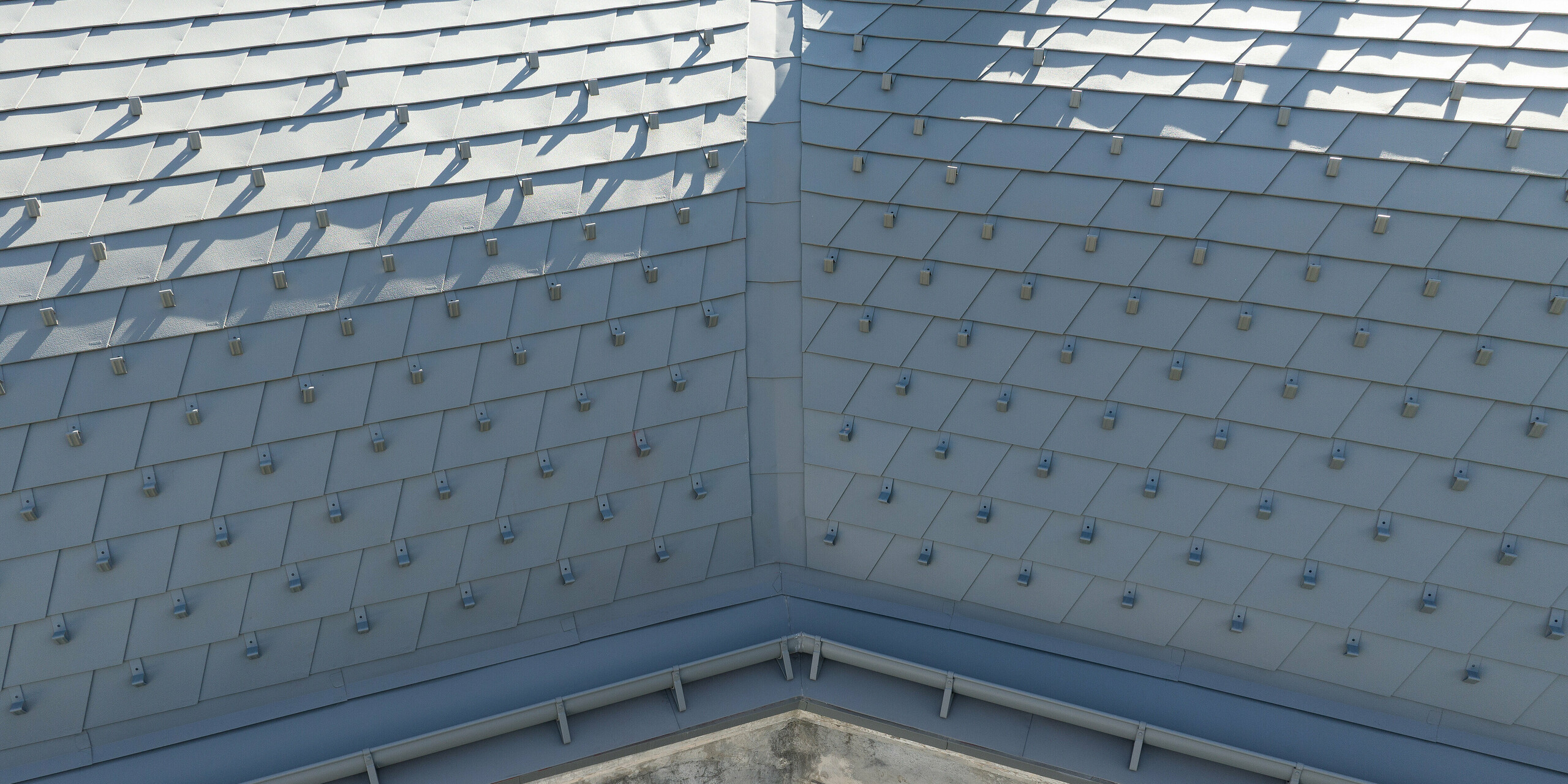 Vue détaillée des bardeaux de toiture PREFA en P.10 gris souris dans un projet de rénovation complexe à Barcelonnette, France.