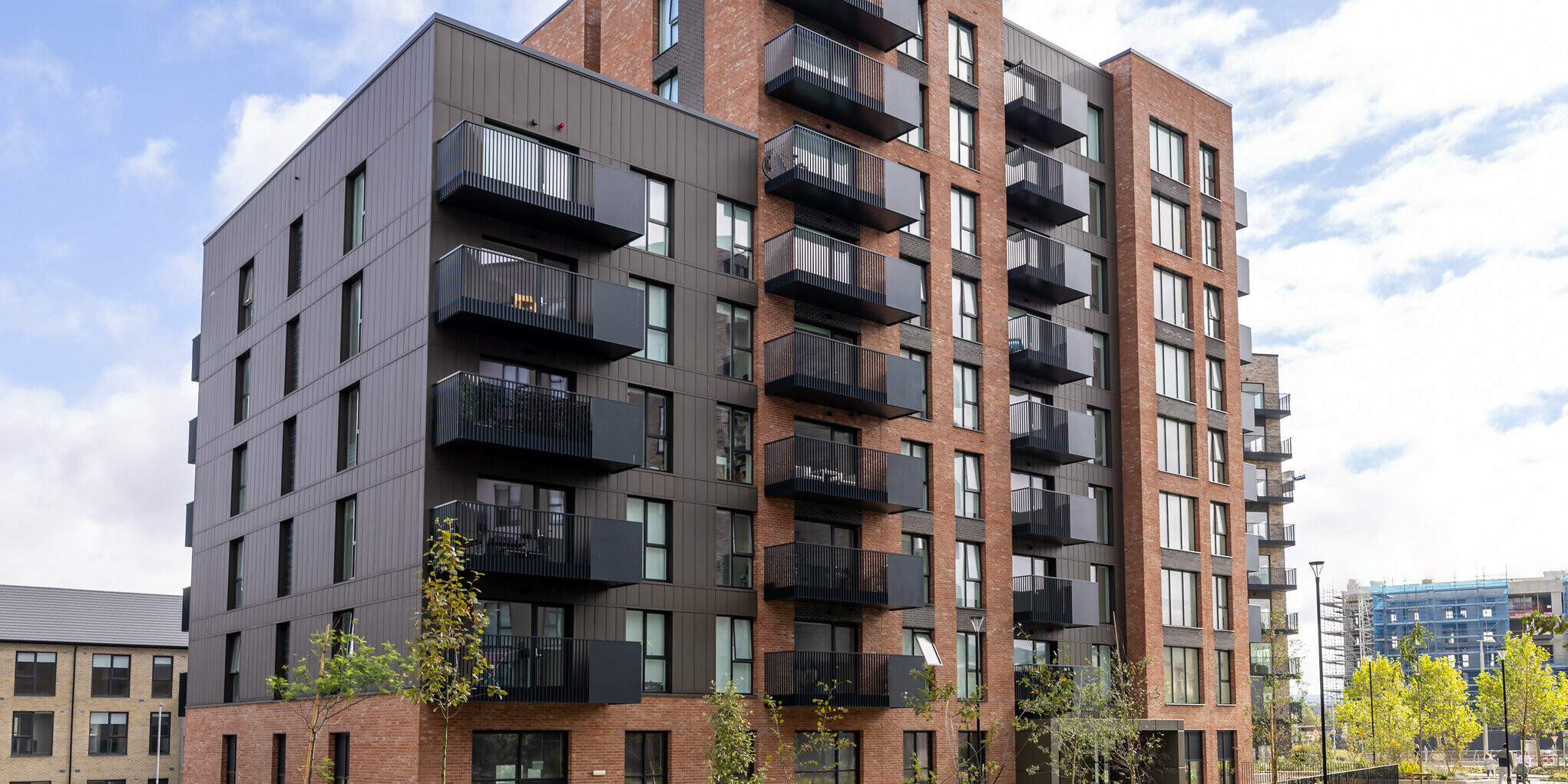 Vue de face des Citywest Apartments à Dublin. Combinaison d'une façade en briques traditionnelle et de 700 m² de revêtements PREFA en tôle de haute qualité de couleur P.10 brun. Les panneaux en aluminium confèrent au bâtiment résidentiel un aspect moderne et urbain avec une grande résistance aux intempéries.