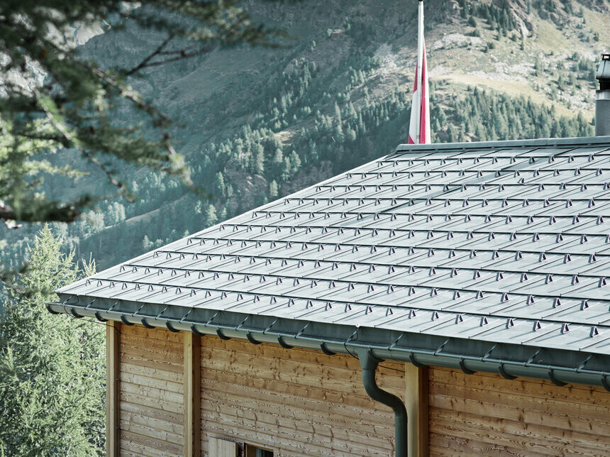 Chalet suisse recouvert de tuile PREFA, avec la gouttière demi-ronde PREFA fixée avec la bride de renfort.