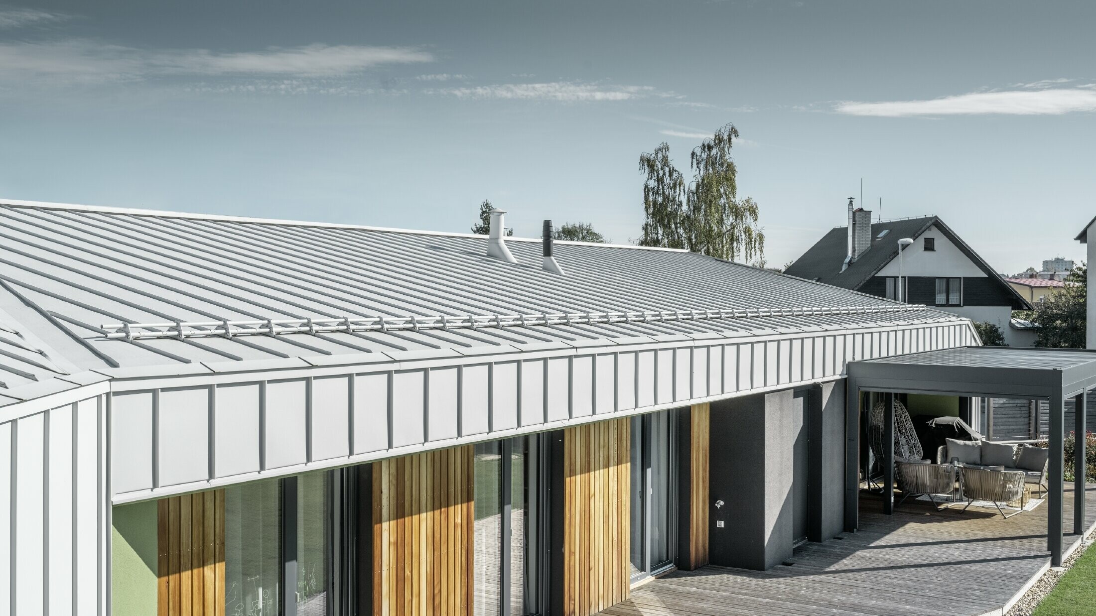 Bungalow avec toit et façade PREFALZ couleur blanc Prefa et terrasse en bois