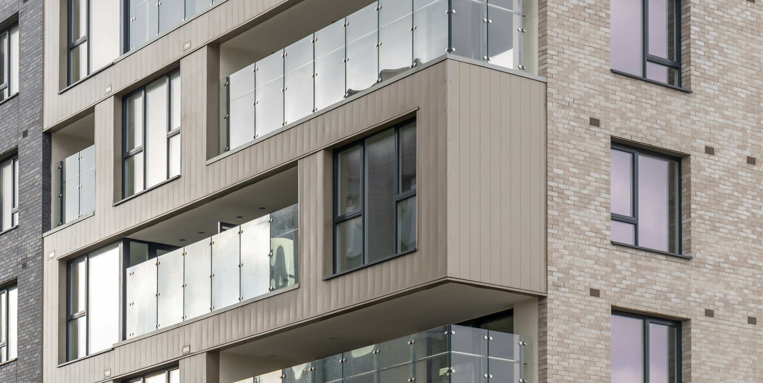 Immeuble d'appartements dans le complexe résidentiel Palmers Gate à Palmerstown, Dublin, Irlande. La façade du bâtiment est revêtue de bardage PREFA de couleur bronze et d'éléments en brique. Les balcons avec balustrades en verre s'étendent sur plusieurs étages, offrant aux résidents des espaces extérieurs modernes et sécuritaires. Au total, environ 1 700 m² de revêtement PREFA et environ 1 200 m² de système de façade PREFALZ ont été utilisés, qui impressionnent par leur robustesse et leur design esthétique. La combinaison de tôles de haute qualité et de briques crée un aspect harmonieux et élégant. 