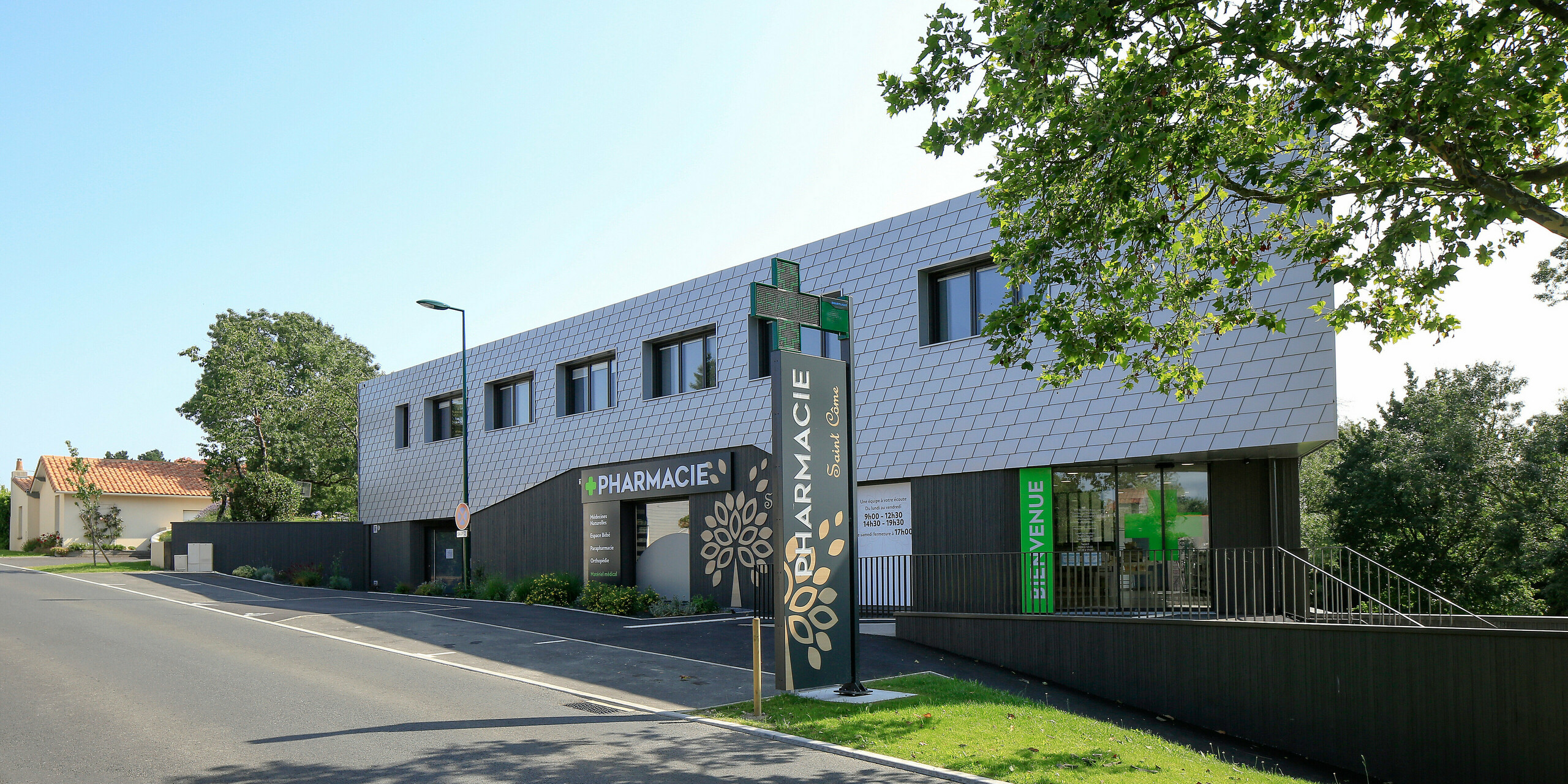 Zugang zur Apotheke im Erdgeschoß des Gesundheitszentrums in Le Landreau mit einer Fassade aus PREFA Wandschindeln in Silbermetallic