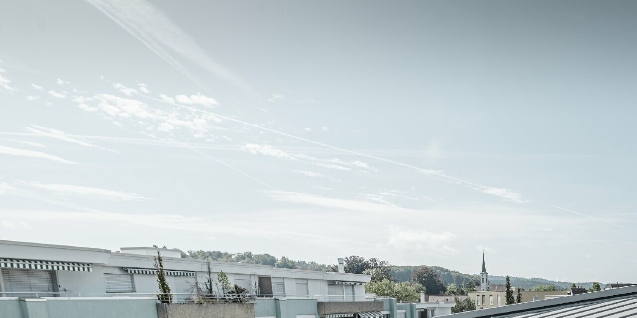 Vue détaillée de la surface de toiture d’un immeuble collectif ; toit à joint debout réalisé avec Prefalz PREFA couleur gris quartz.