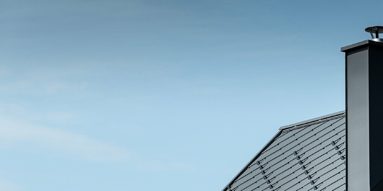 Maison individuelle au toit à deux versants sans saillie de toit — Façade à l’aspect du bois et toiture en aluminium PREFA de couleur anthracite