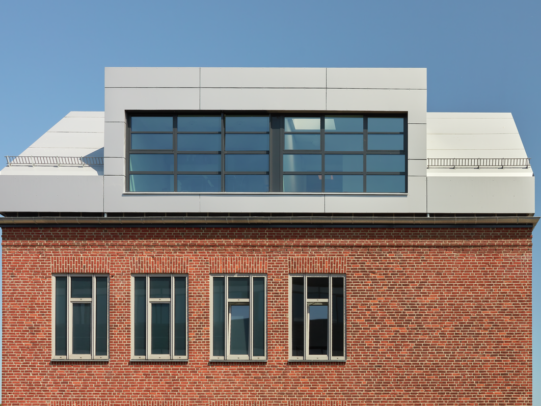 In der Abbildung sind die PREFABOND Aluminium Verbundplatten in Silbermetallic und Anthrazit zu sehen. Diese wurden auf das Backsteingebäude einsteineins im Wissenschaftspark in Kiel montiert.