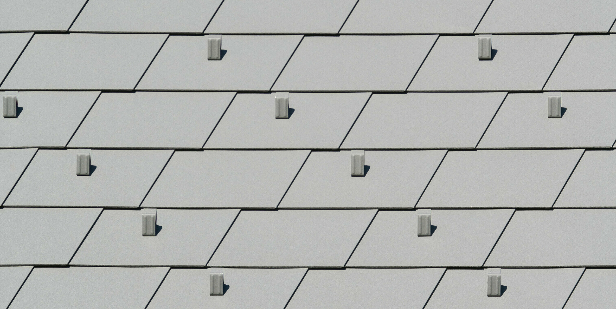 Vue détaillée des bardeaux de toiture PREFA en P.10 gris souris dans un projet de rénovation complexe à Barcelonnette, France.