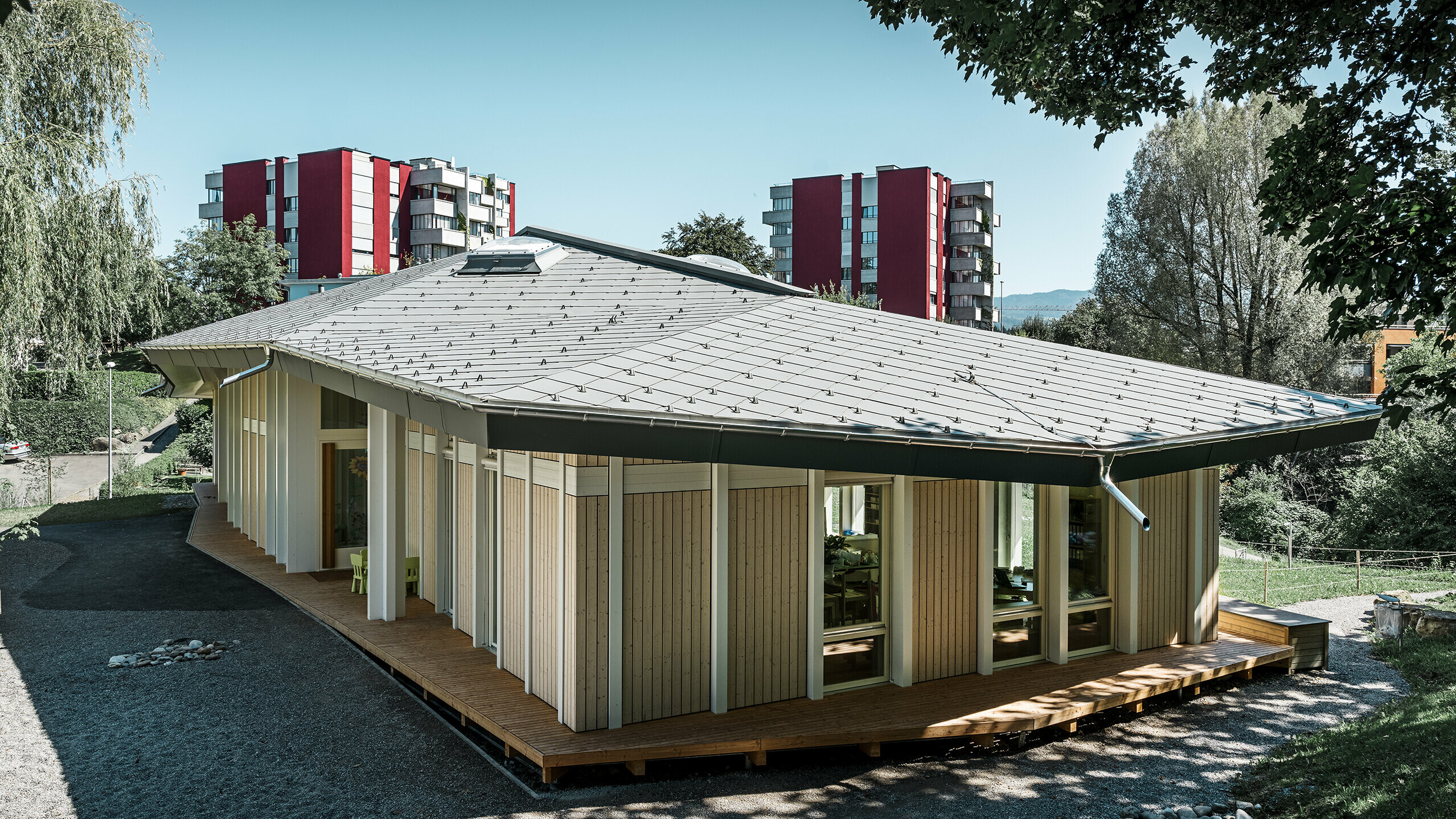 Jardin d’enfants de plain-pied avec panneaux de façade verticaux et toiture en aluminium de PREFA (losange de toiture) couleur gris souris